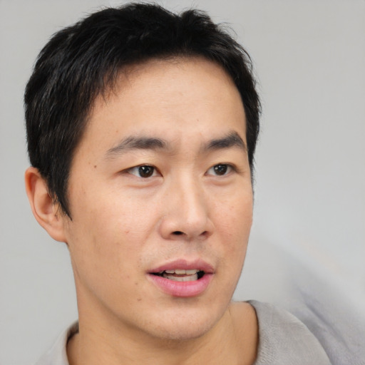 Joyful asian adult male with short  brown hair and brown eyes