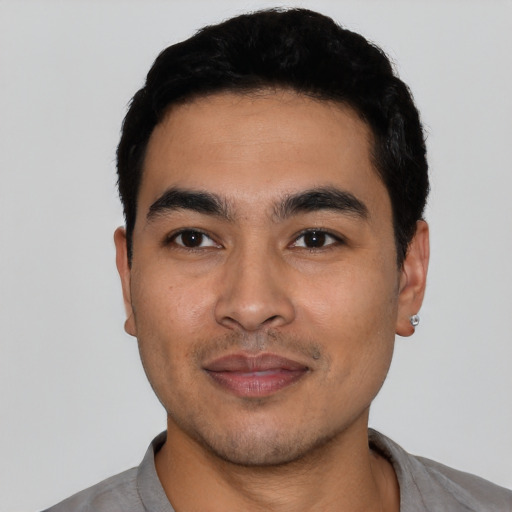 Joyful latino young-adult male with short  black hair and brown eyes