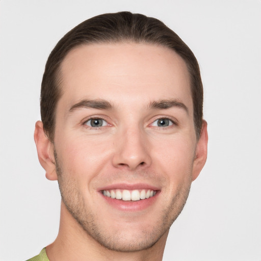 Joyful white young-adult male with short  brown hair and grey eyes