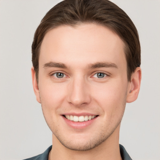 Joyful white young-adult male with short  brown hair and grey eyes