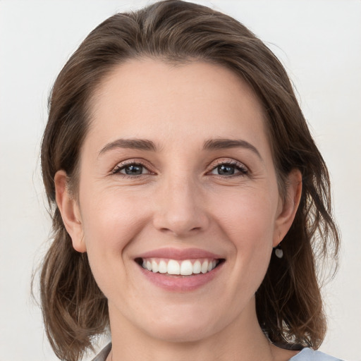 Joyful white young-adult female with medium  brown hair and grey eyes