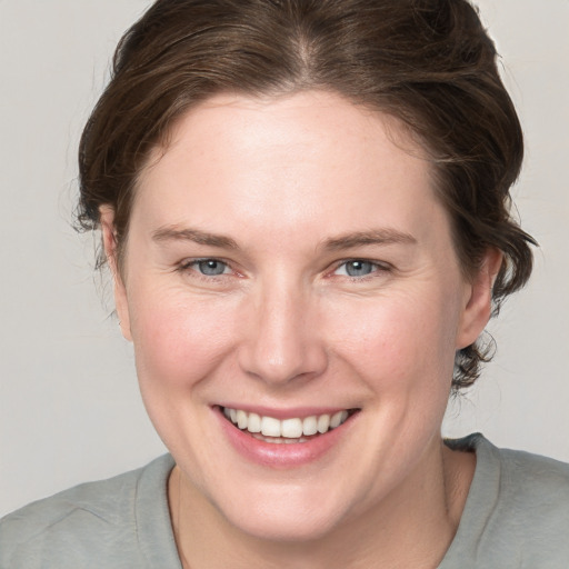 Joyful white young-adult female with medium  brown hair and grey eyes