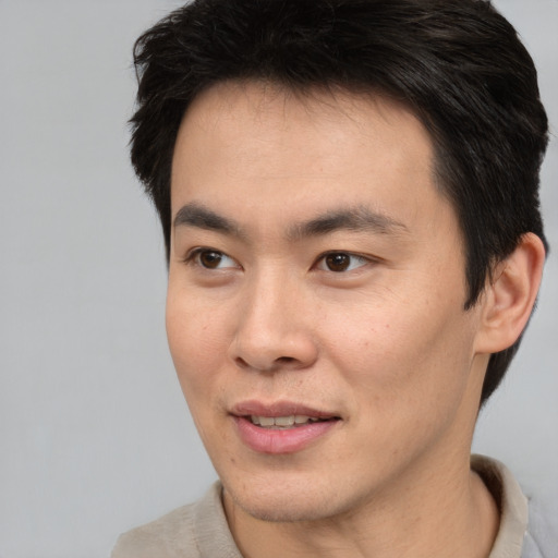 Joyful asian young-adult male with short  brown hair and brown eyes