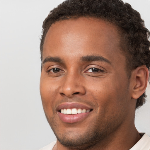 Joyful black young-adult male with short  brown hair and brown eyes