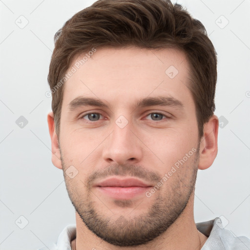 Joyful white young-adult male with short  brown hair and grey eyes