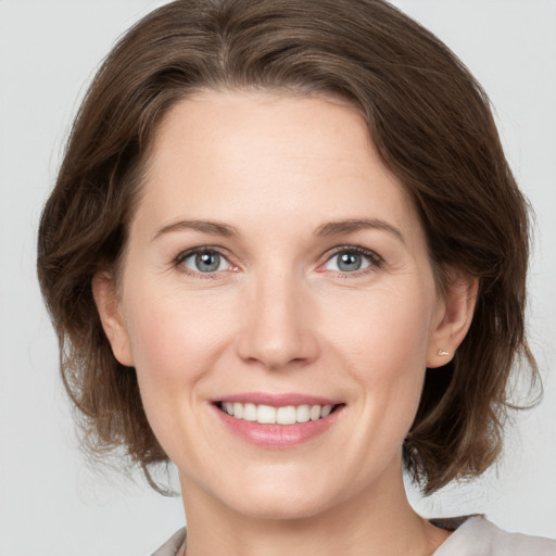 Joyful white young-adult female with medium  brown hair and grey eyes