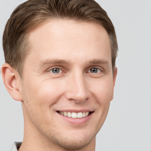 Joyful white young-adult male with short  brown hair and grey eyes