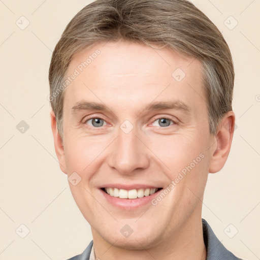 Joyful white young-adult male with short  brown hair and grey eyes