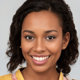 Joyful black young-adult female with long  brown hair and brown eyes