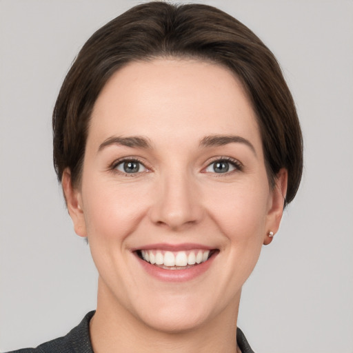 Joyful white young-adult female with short  brown hair and grey eyes