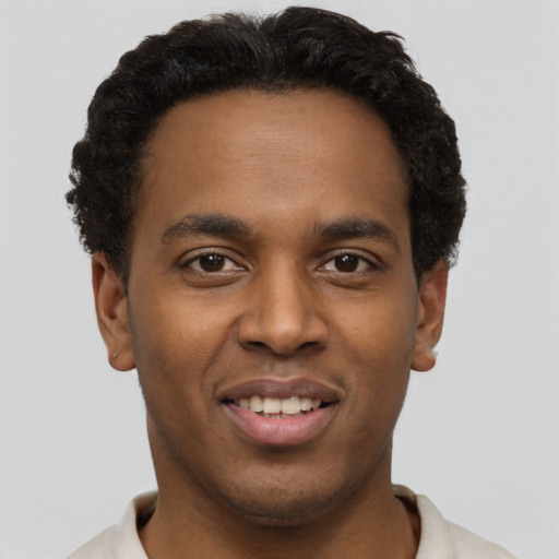 Joyful black young-adult male with short  brown hair and brown eyes