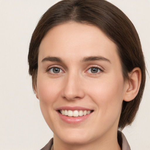 Joyful white young-adult female with medium  brown hair and grey eyes