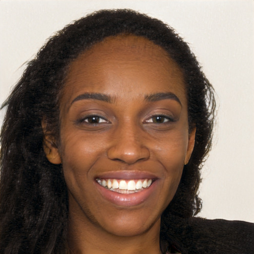 Joyful black young-adult female with long  brown hair and brown eyes