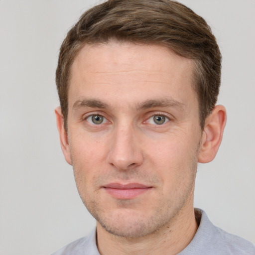 Joyful white young-adult male with short  brown hair and grey eyes