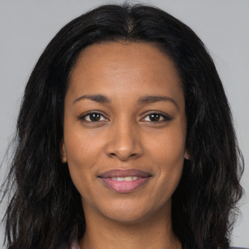 Joyful black young-adult female with long  black hair and brown eyes