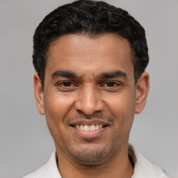 Joyful latino young-adult male with short  black hair and brown eyes