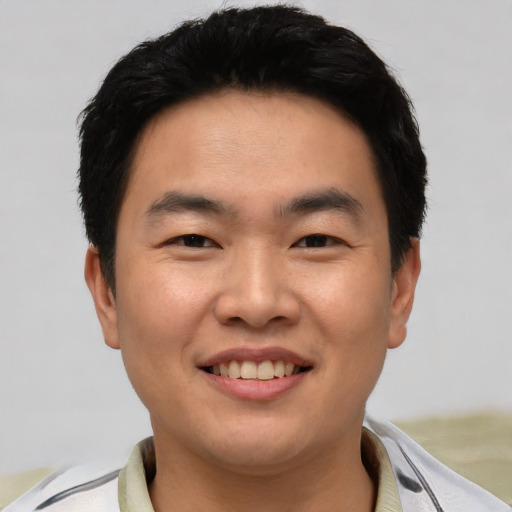 Joyful asian young-adult male with short  black hair and brown eyes