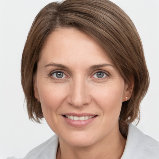 Joyful white young-adult female with medium  brown hair and grey eyes