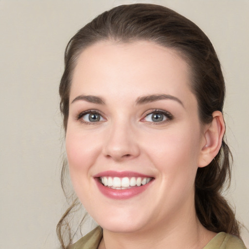 Joyful white young-adult female with medium  brown hair and grey eyes