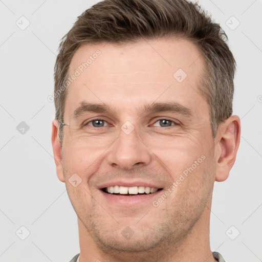 Joyful white young-adult male with short  brown hair and grey eyes