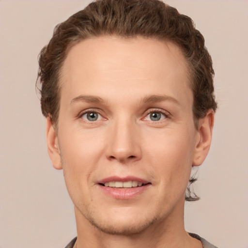 Joyful white young-adult male with short  brown hair and grey eyes