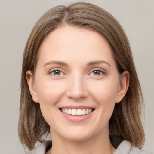 Joyful white young-adult female with medium  brown hair and grey eyes