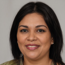 Joyful latino adult female with medium  brown hair and brown eyes