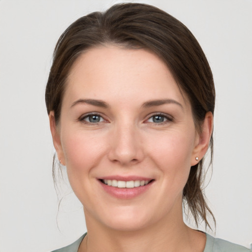 Joyful white young-adult female with medium  brown hair and grey eyes