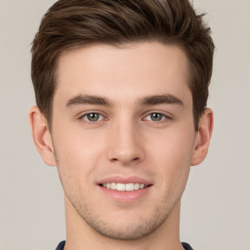 Joyful white young-adult male with short  brown hair and grey eyes