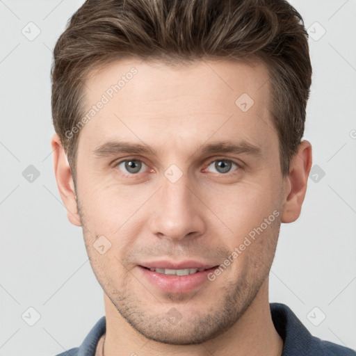 Joyful white young-adult male with short  brown hair and grey eyes