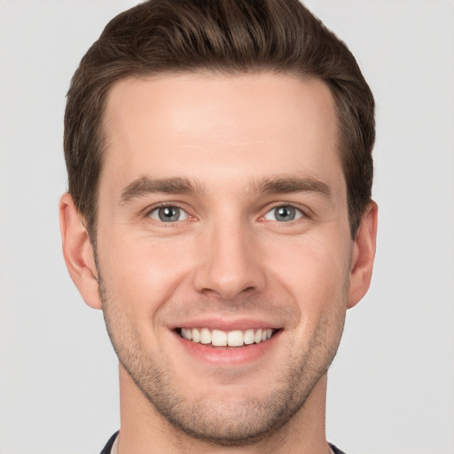 Joyful white young-adult male with short  brown hair and grey eyes