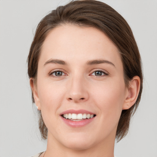 Joyful white young-adult female with medium  brown hair and grey eyes