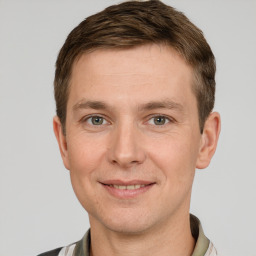 Joyful white young-adult male with short  brown hair and grey eyes