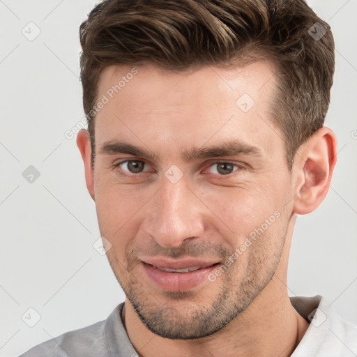 Joyful white young-adult male with short  brown hair and grey eyes