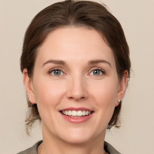 Joyful white young-adult female with medium  brown hair and grey eyes