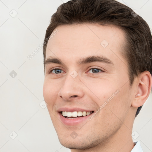 Joyful white young-adult male with short  brown hair and grey eyes