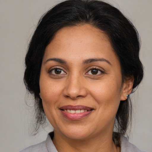Joyful latino adult female with medium  brown hair and brown eyes