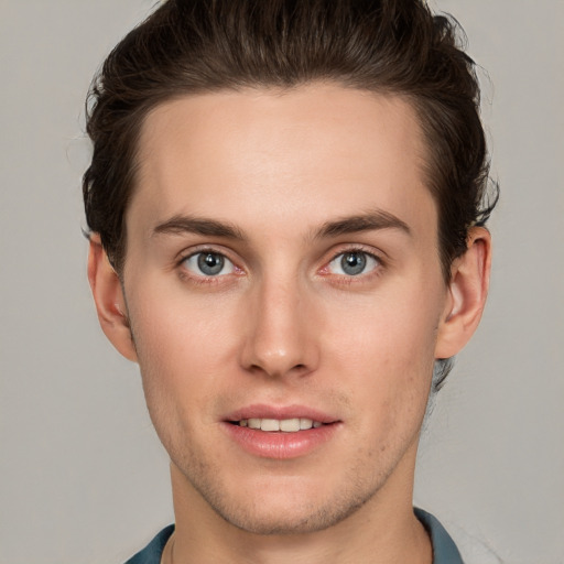 Joyful white young-adult male with short  brown hair and grey eyes