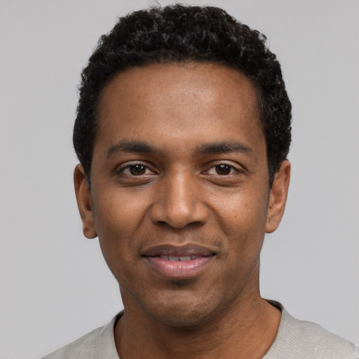Joyful black young-adult male with short  black hair and brown eyes