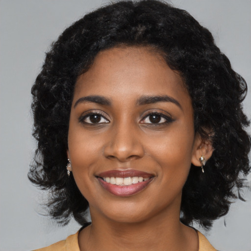 Joyful black young-adult female with long  black hair and brown eyes