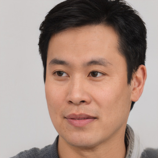 Joyful asian young-adult male with short  black hair and brown eyes
