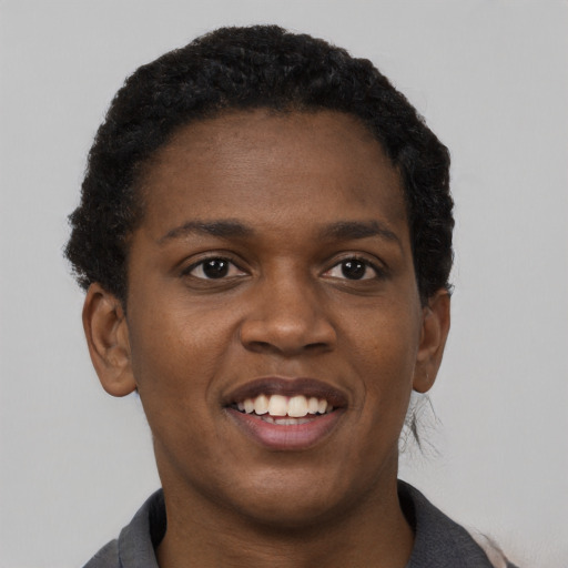 Joyful black young-adult female with short  black hair and brown eyes