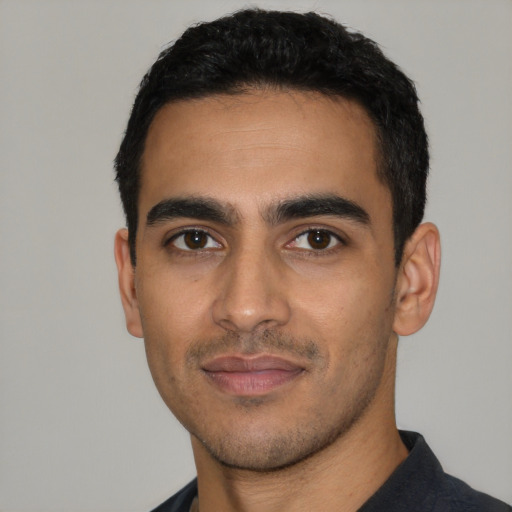 Joyful latino young-adult male with short  black hair and brown eyes