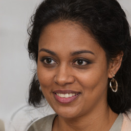 Joyful black young-adult female with long  brown hair and brown eyes