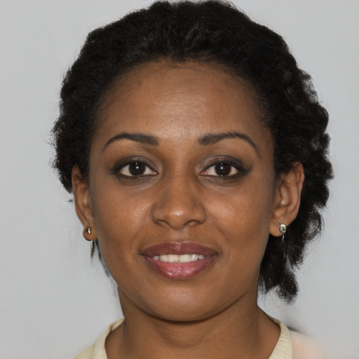 Joyful black young-adult female with short  black hair and brown eyes