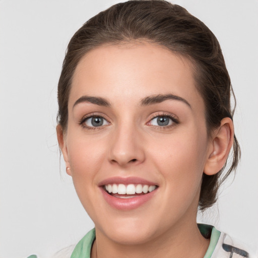 Joyful white young-adult female with medium  brown hair and grey eyes