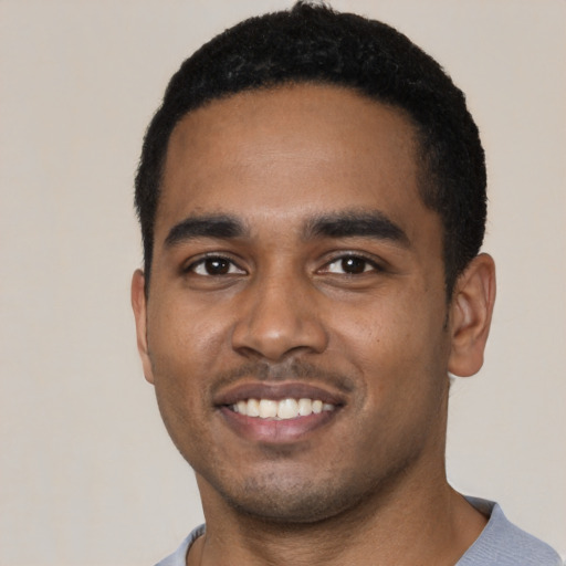 Joyful black young-adult male with short  black hair and brown eyes