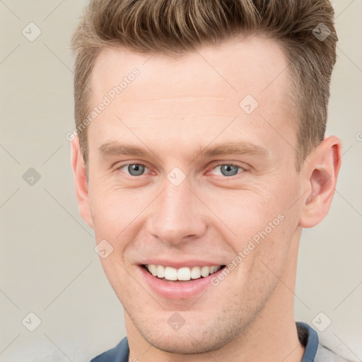 Joyful white young-adult male with short  brown hair and grey eyes