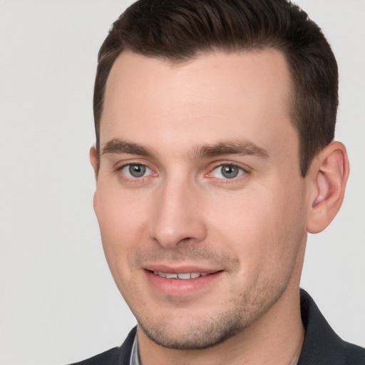 Joyful white young-adult male with short  brown hair and grey eyes