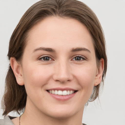 Joyful white young-adult female with medium  brown hair and grey eyes